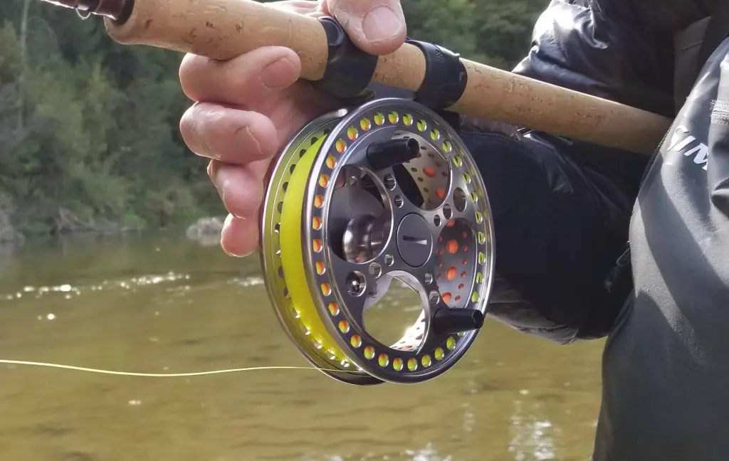 A close up of an angler holding a Centerpin rod and reel and the reel is slowly spinning