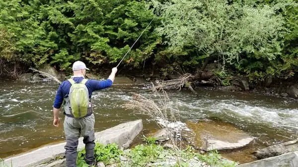 An angler indicator nymphing in fast water with a high rod tip position for better control.