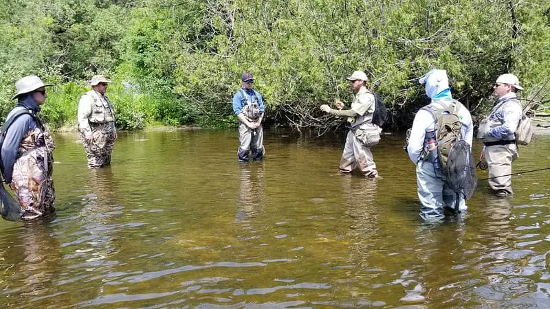 A top guide explaining what Is fly fishing to a group of anglers