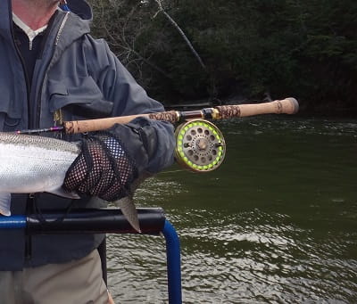 An angler holding a Centerpin Reel on a rod with a built in reel seat