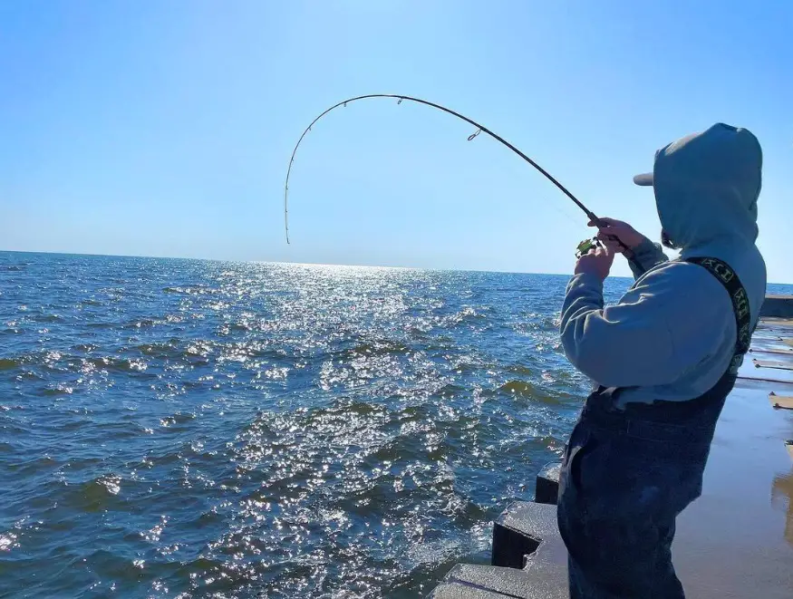 An angler Lake Michigan Fishing from a pier.