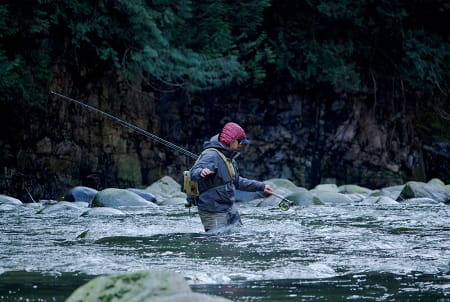 An angler wading across a fast river.