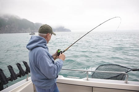An angler salmon fishing from a boat in the ocean.