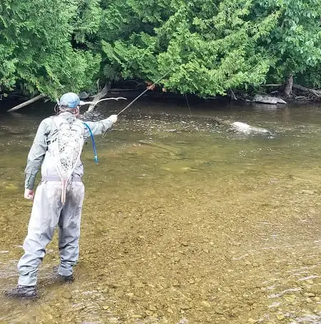 an angler nymphing behind a rock in a trout stream.