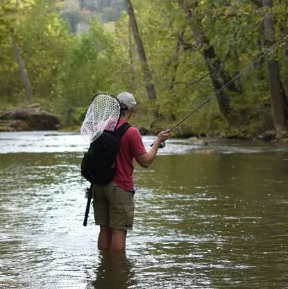 An angler with a long handle trout net.