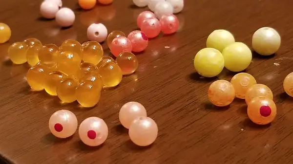 My favorite hard plastic trout beads beside real salmon eggs.