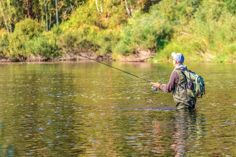 An angler deep in the water trout fishing with Powerbait