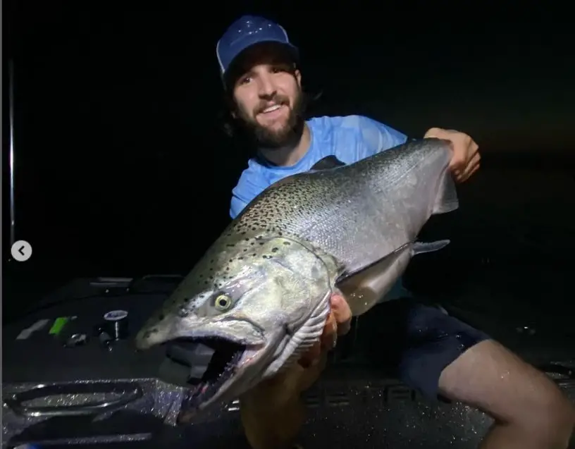 John from Get Bent Guide service with a big salmon caught while salmon fishing at night.