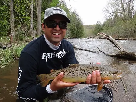 An angler with a nice brown trout caught while wet wading. The right wet wading gear can make your wet wading trip safer and better.