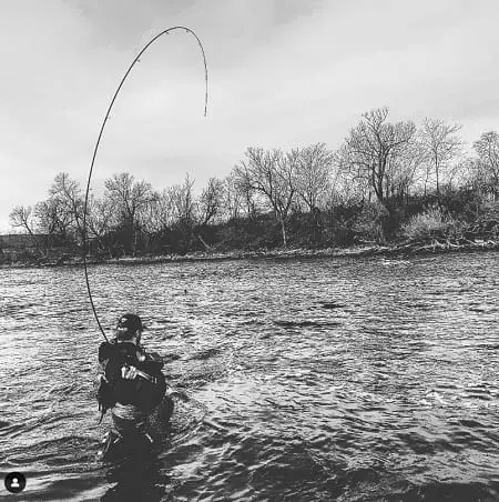 An angler fighting a fish with a long bent-over float rod.