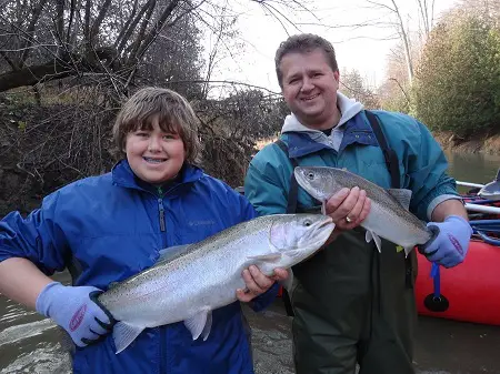 A picture of two of my clients with the Berkley gloves on holding their big steelhead.