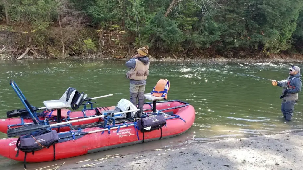 The authors fly fishing boat with a client standing and fighting a big steelhead.